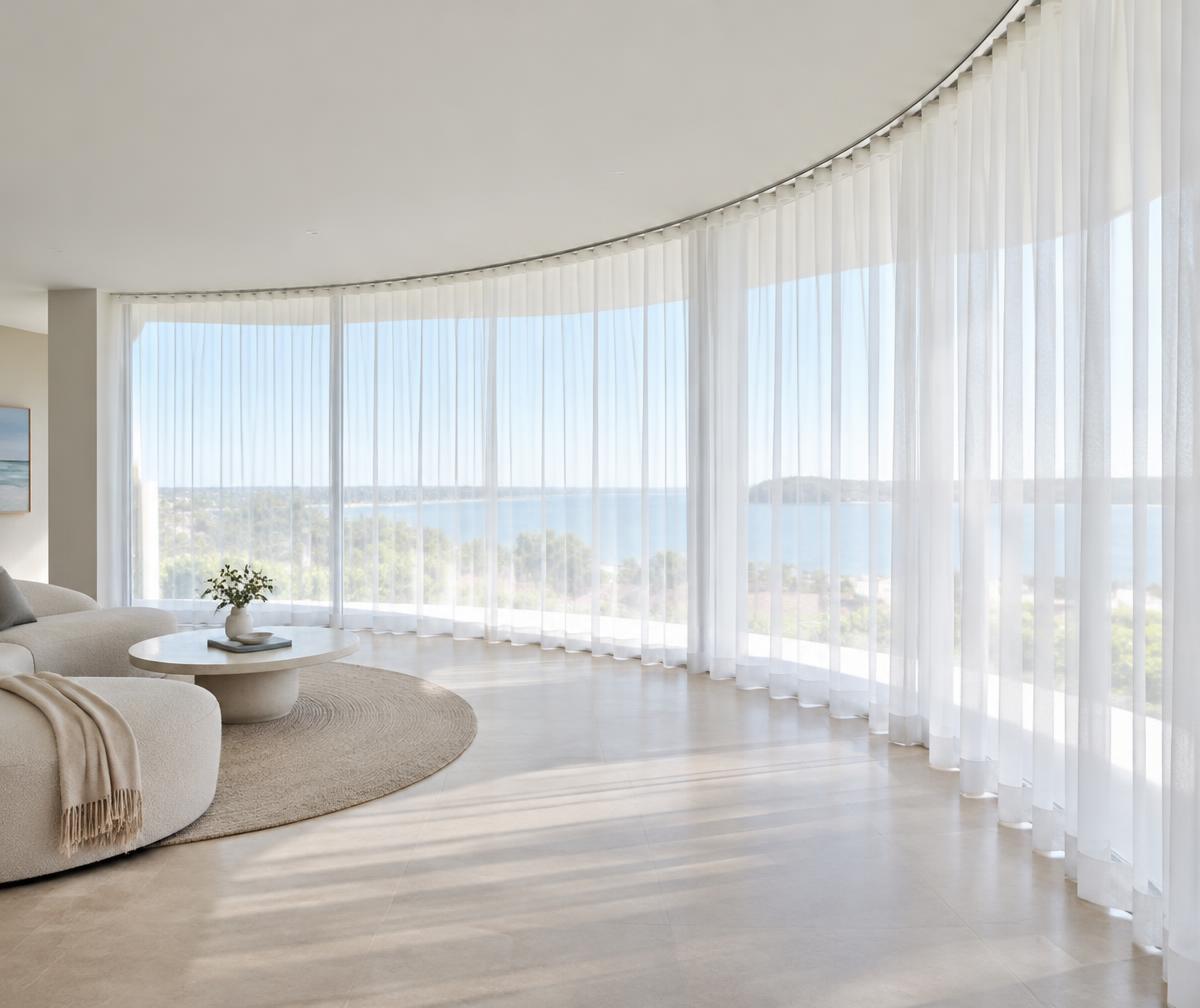 Illustrative sheer curtains following a smooth curved ceiling track and rounded window wall